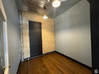 Empty room featuring brick wall and dark wood-style floors