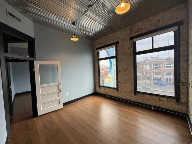 Empty room with brick wall and dark wood-style flooring