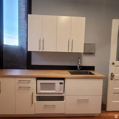 Kitchen featuring white cabinetry, white microwave, and dark wood finished floors
