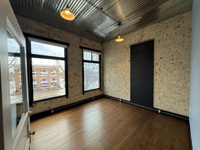 Unfurnished room with brick wall and dark wood-style floors