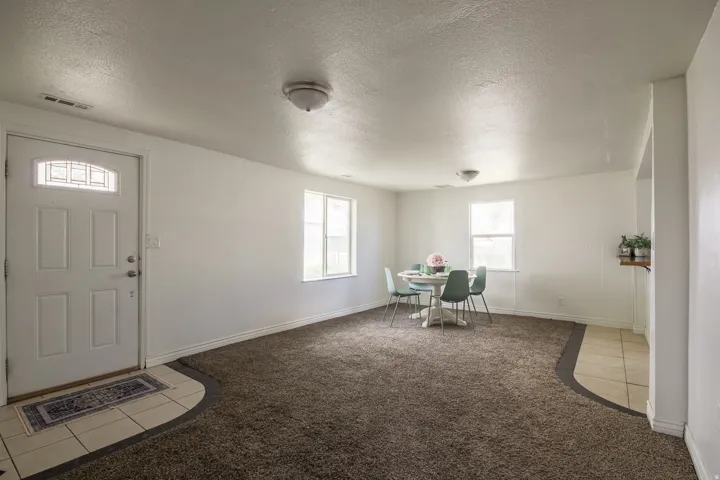 Entryway with carpet flooring, tile patterned floors, and a textured ceiling