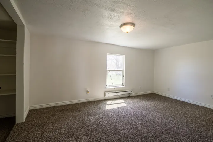 Unfurnished room featuring a textured ceiling, dark colored carpet, and baseboard heating