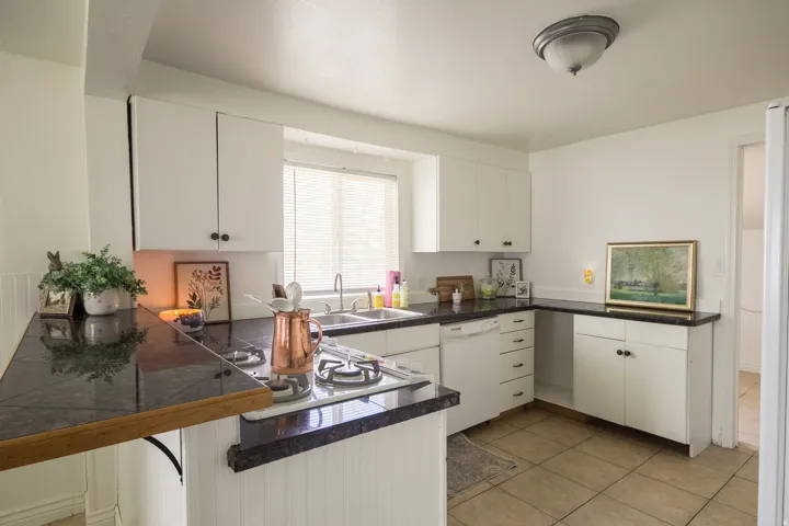Kitchen featuring white cabinetry, dishwasher, tile countertops, and light tile patterned floors