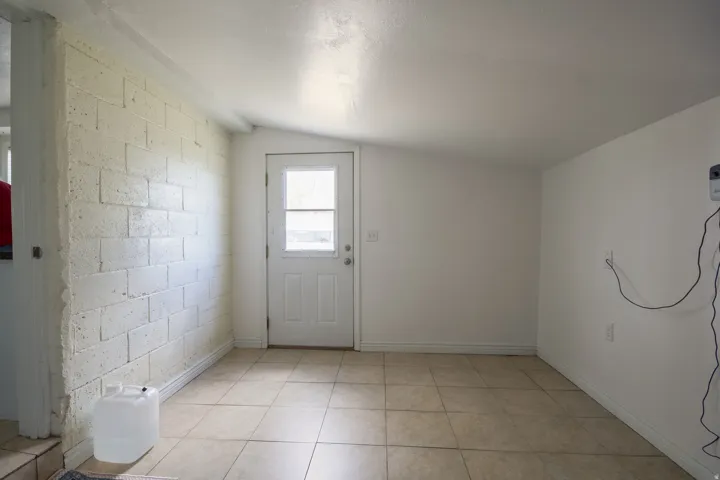 Entryway featuring concrete block wall, lofted ceiling, and tile patterned floors
