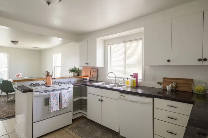 Kitchen with white appliances, a peninsula, white cabinets, and tile patterned floors