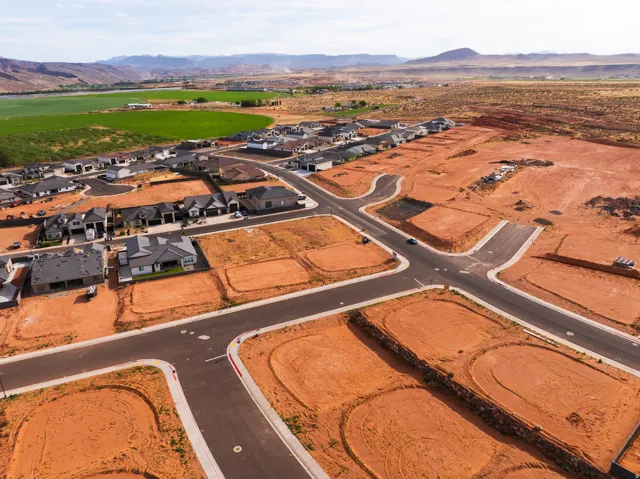 Aerial view of property and surrounding area featuring a mountainous background and nearby suburban area