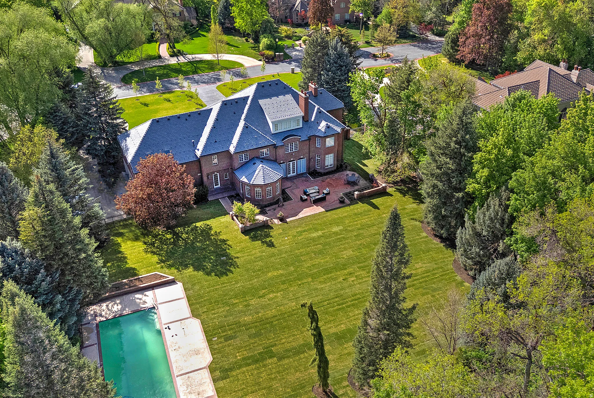View from above of property featuring a tree filled landscape, pool and huge yard.