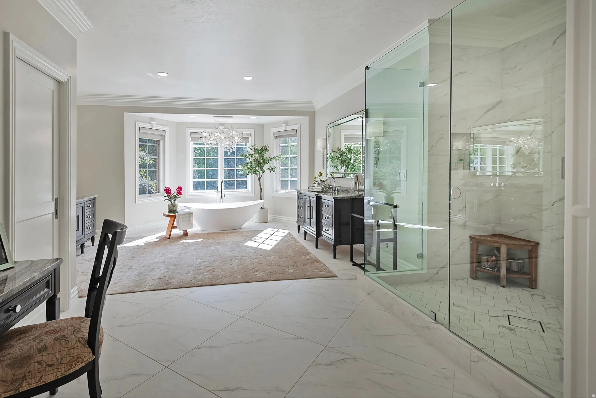 Primary ensuite bathroom. Inspired by the finest spa like quality, with dual vanities, heated floors, crown molding, tile floors, a marble finish shower, and a soaking tub surrounded by charming paned windows.