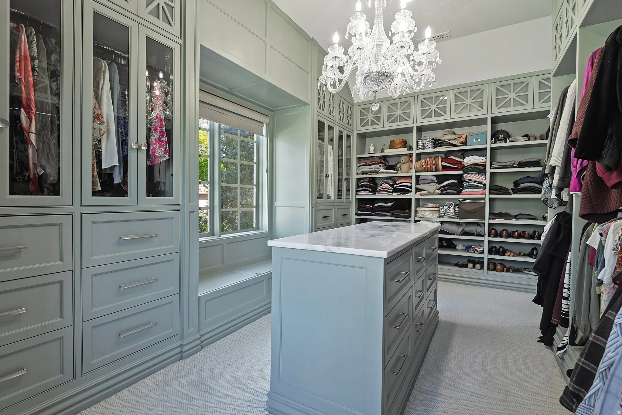Exclusive boutique inspired primary Walk in closet featuring custom builtins, chandelier and natural light