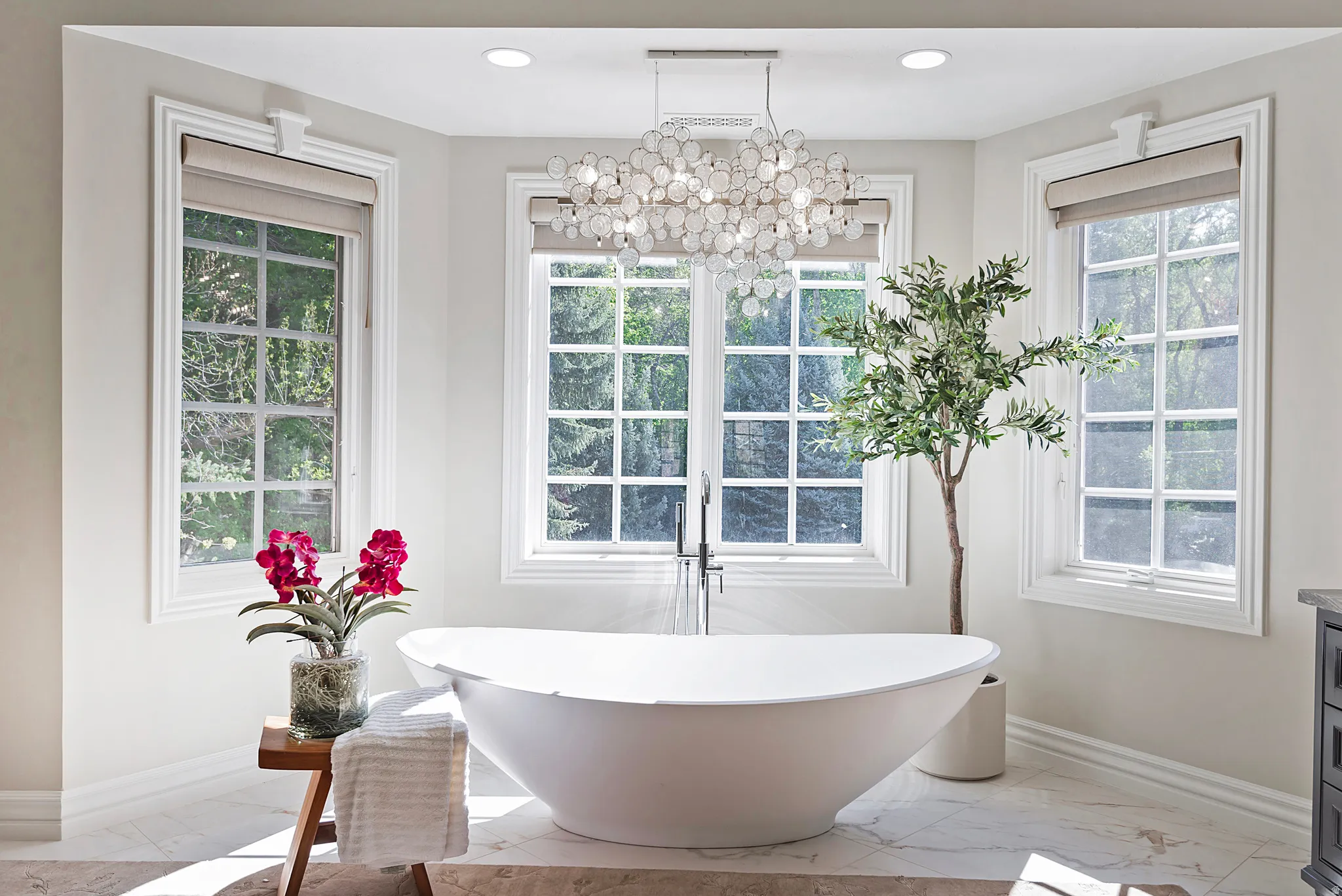 Charming soaking tub with natural light, elegant chandelier, overlooking a very private and secluded backyard.