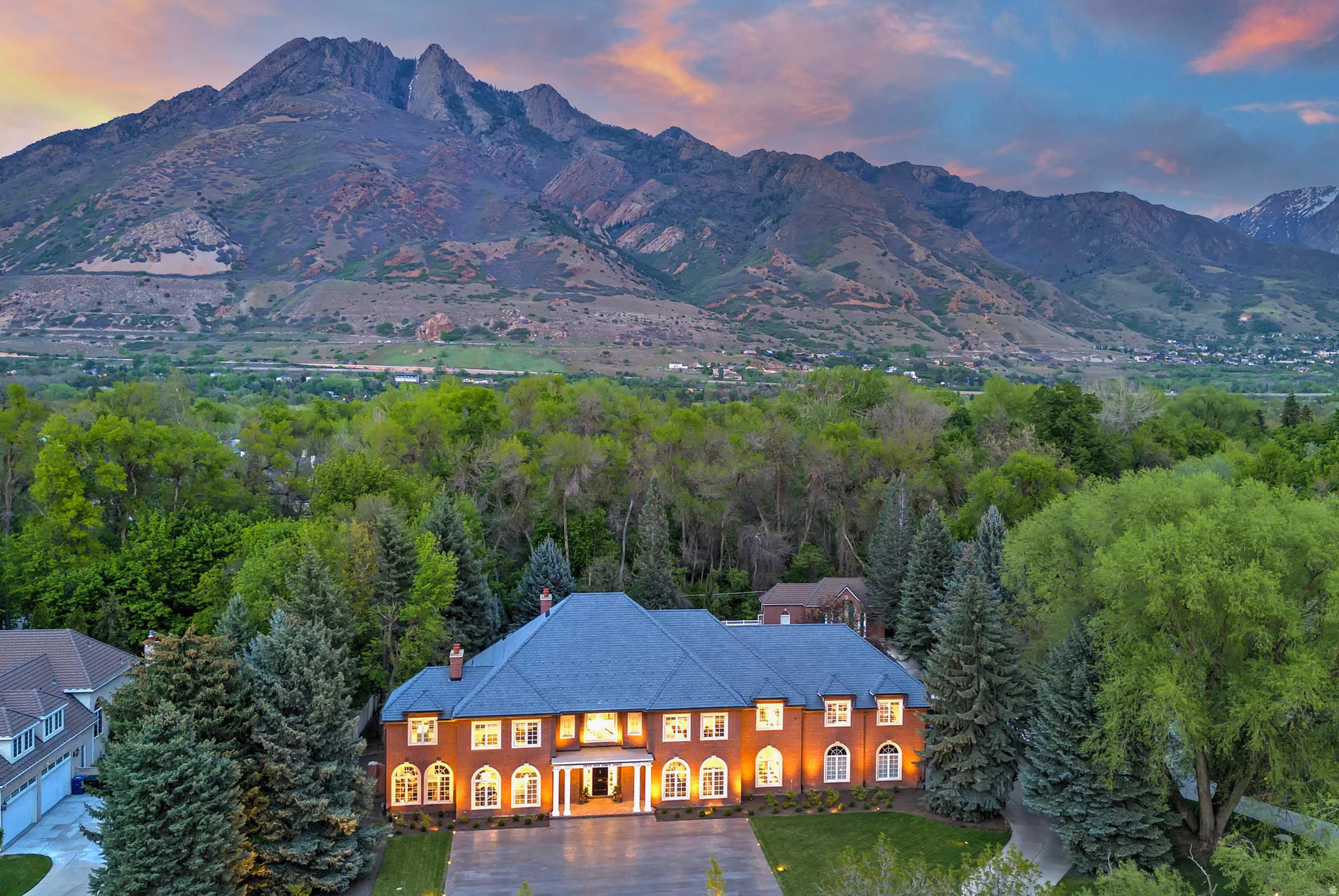 Aerial view at dusk of the breathtaking Wasatch Front mountain range backing this estate