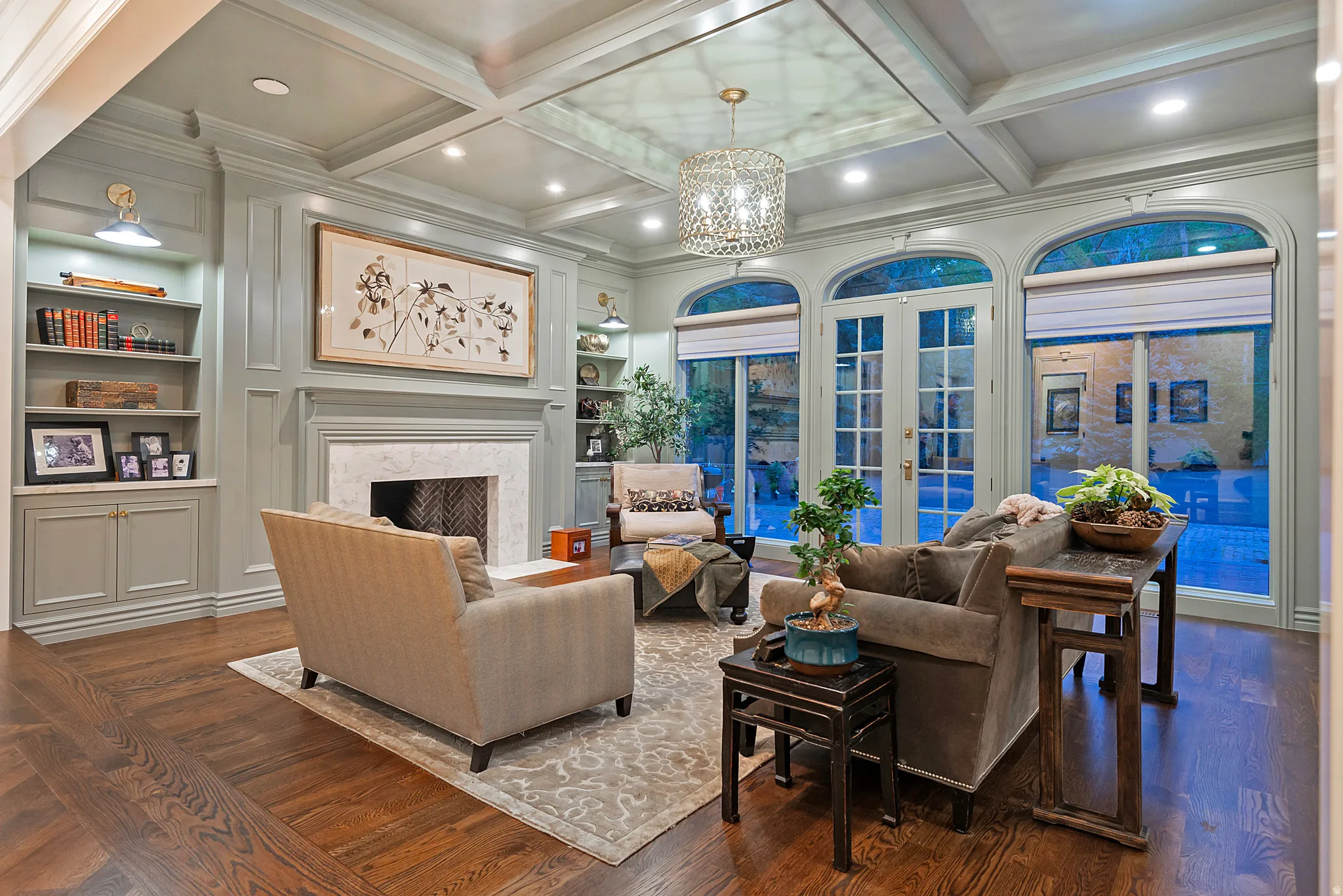Family room offers built in features, ornamental molding, wood floors, a fireplace, and coffered ceiling