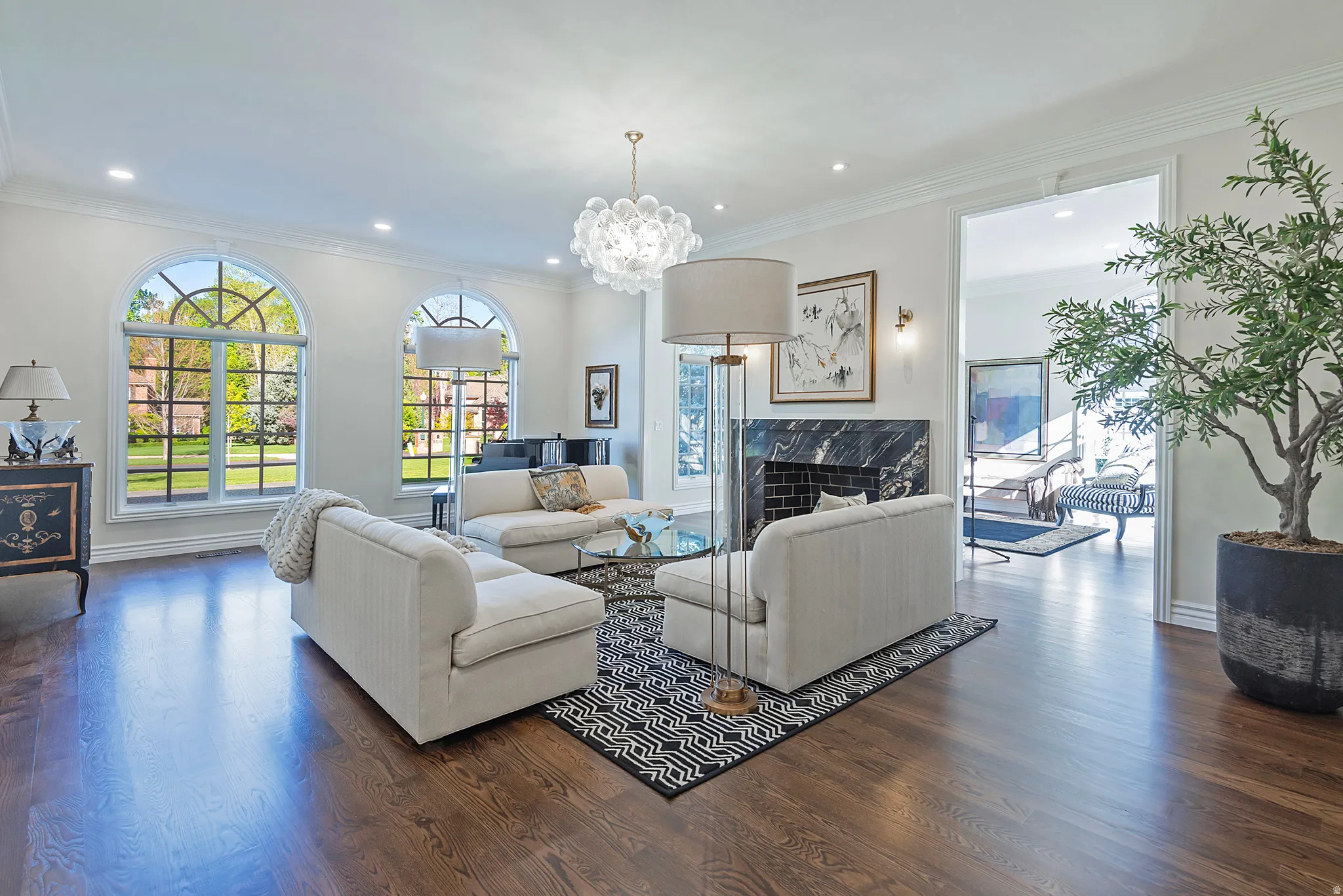 Living room featuring  gleaming wood flooring, ornamental molding, fireplace and so much natural light.
