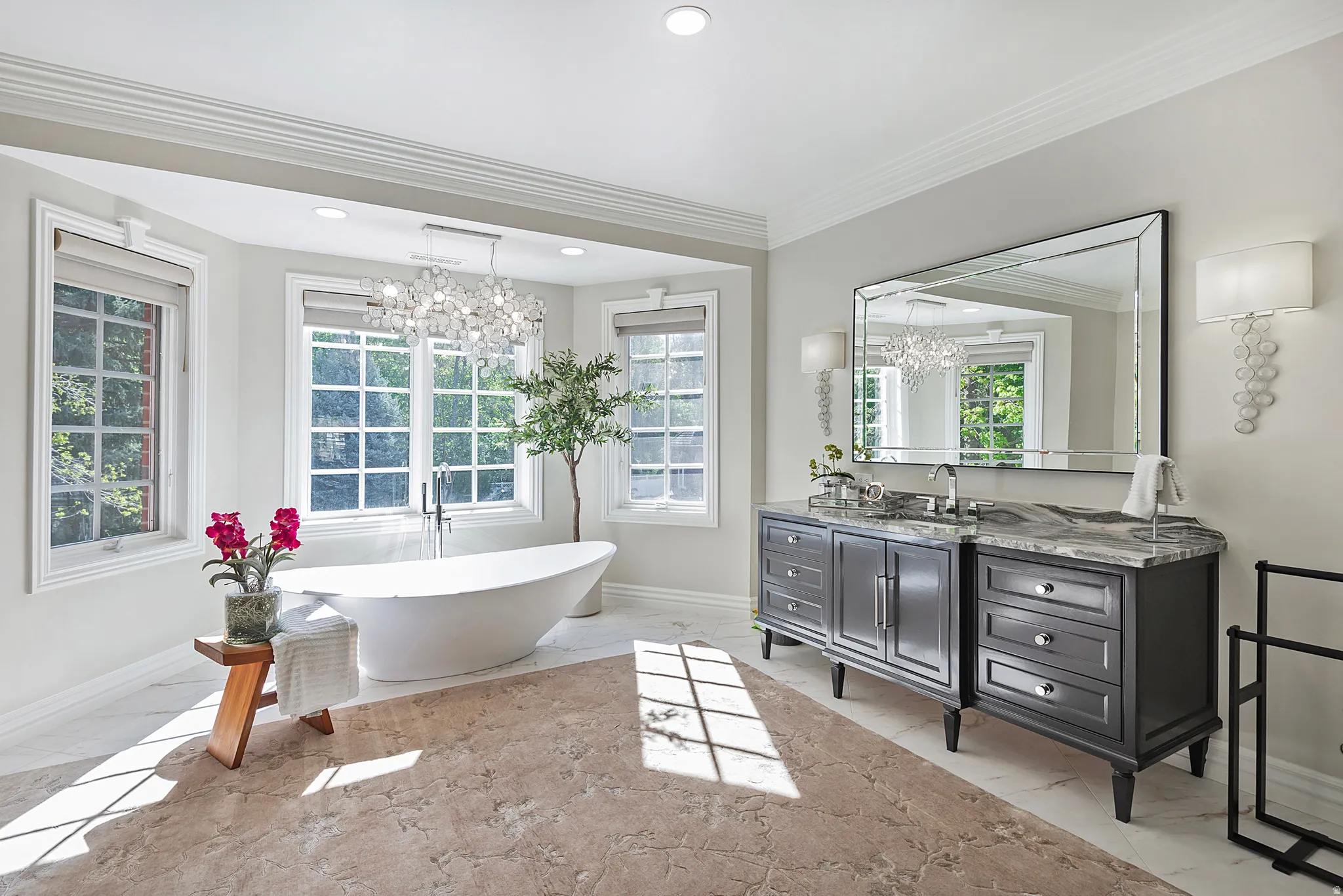 Primary ensuite bathroom. Inspired by the finest spa like quality, with heated floors, dual vanities, crown molding, tile floors, a marble finish shower, and a soaking tub surrounded by charming paned windows.