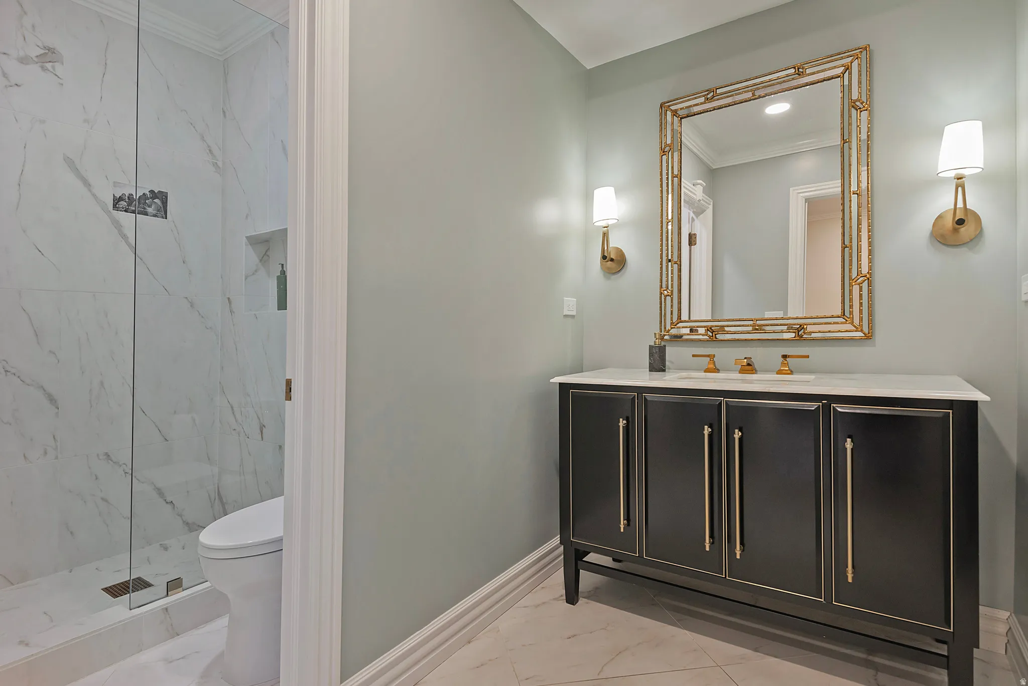 Elegant bathroom with crown molding, vanity, light marble finish flooring, and a marble finish shower