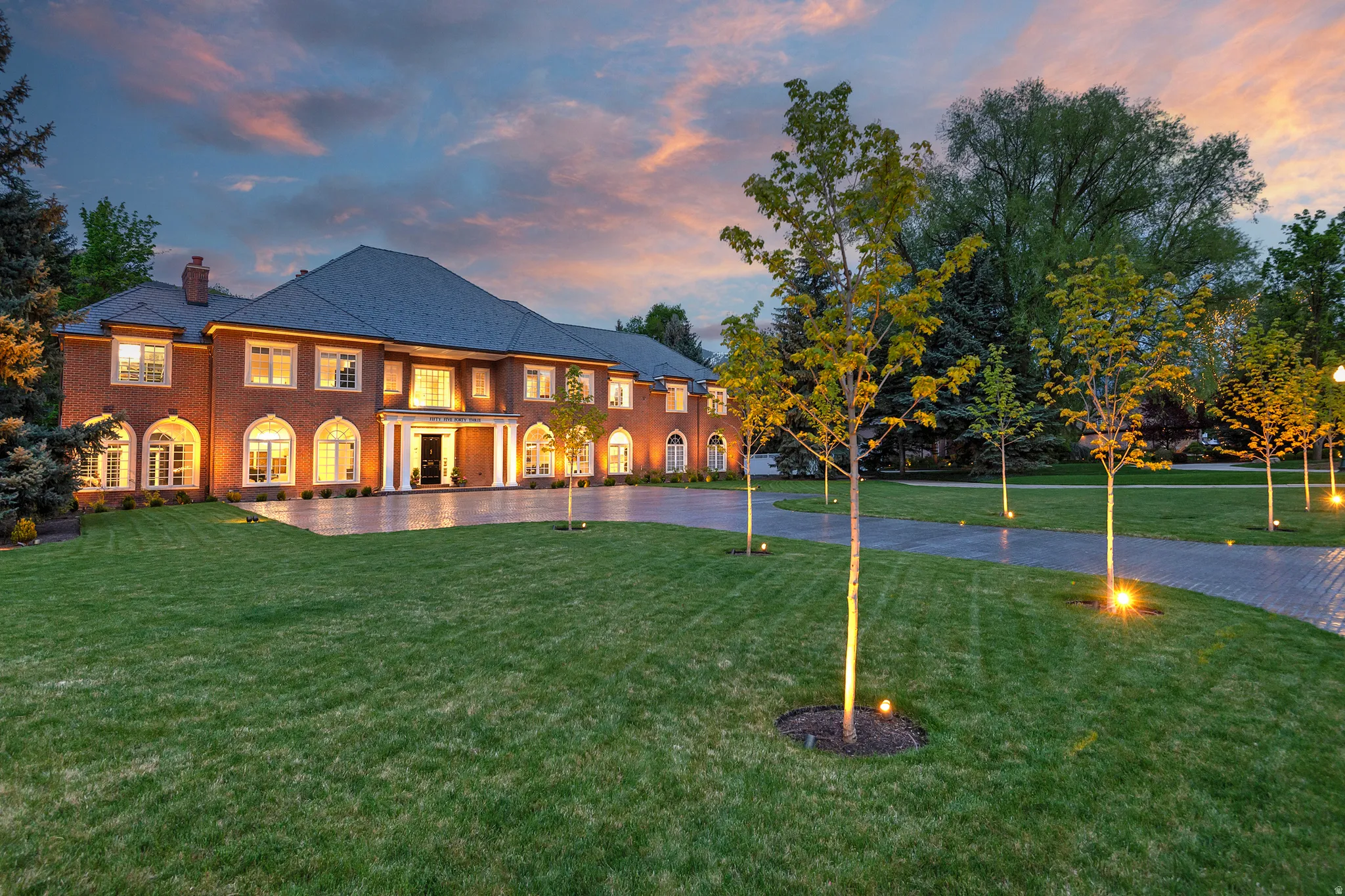 Property at dusk featuring expansive lawn and courtyard.  The curb appeal is second to none!