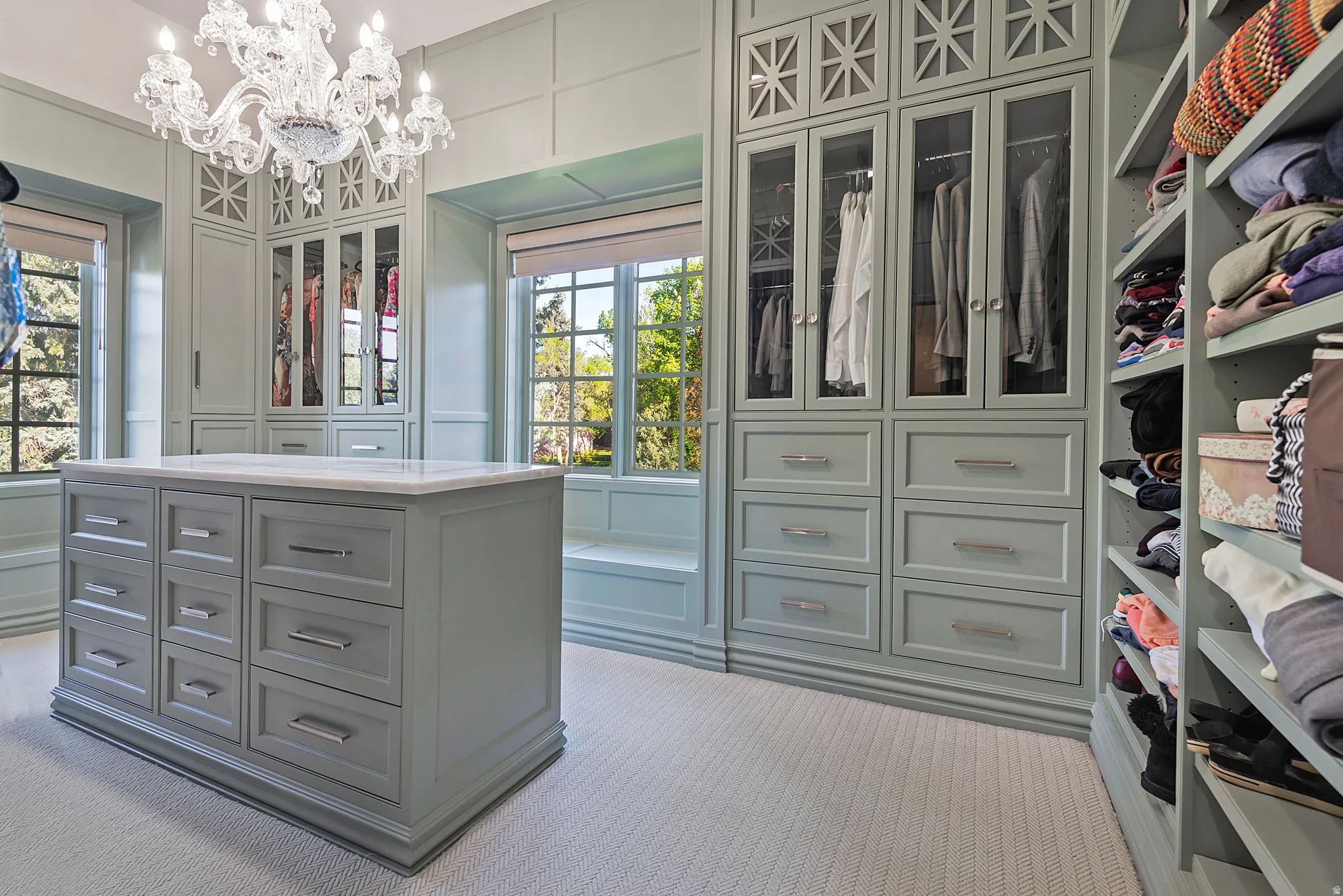 Exclusive boutique inspired primary Walk in closet featuring custom builtins, chandelier and natural light