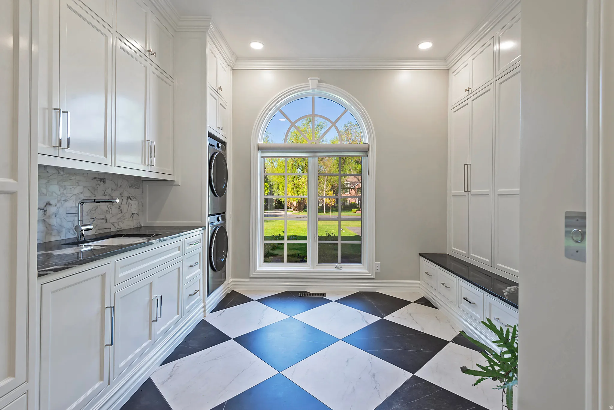 First laundry area with locker cabinet space, crown molding, stacked washer and dryer, space and recessed lighting
