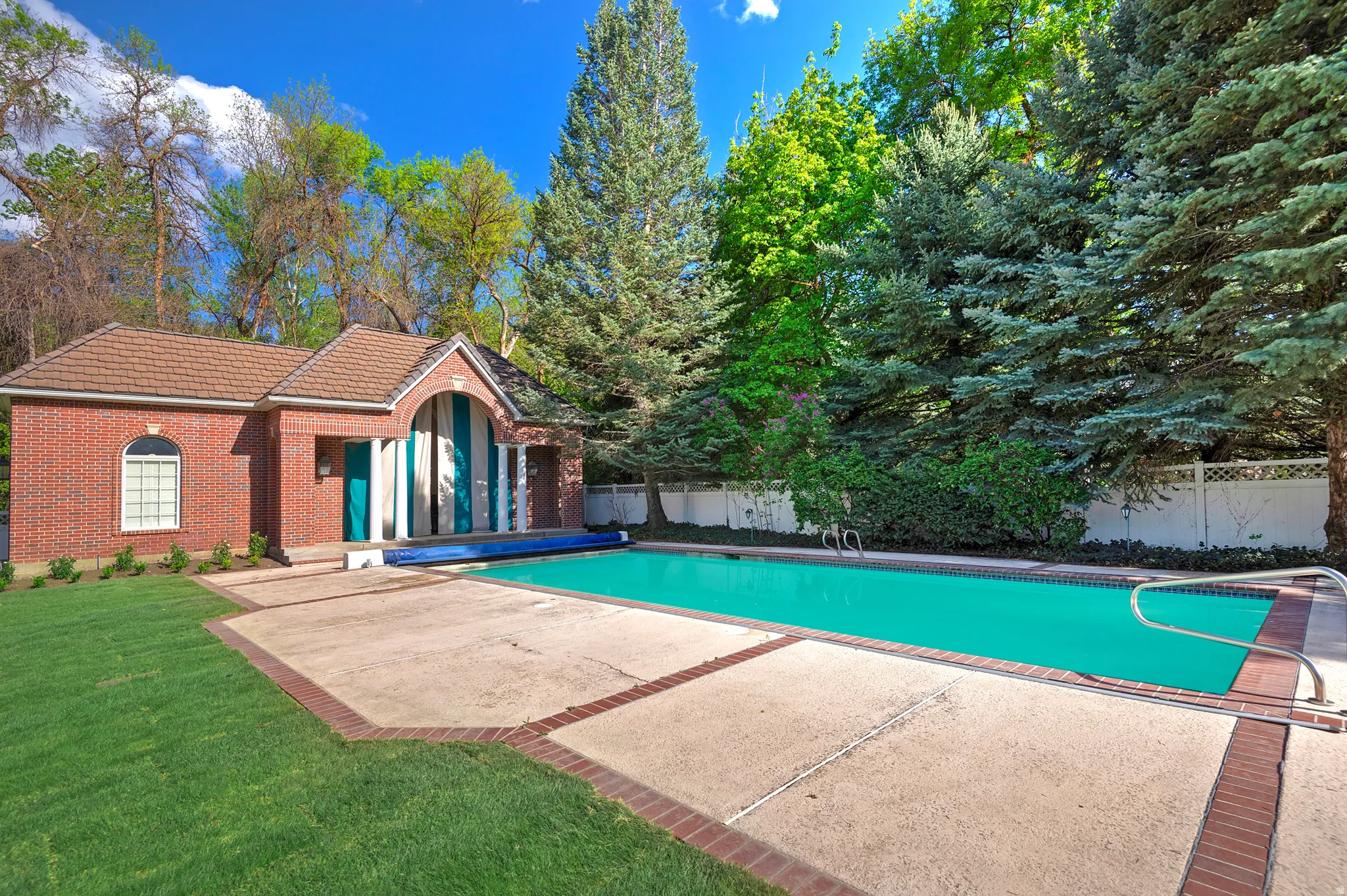 Swimming pool featuring expansive patio area and a pool house.