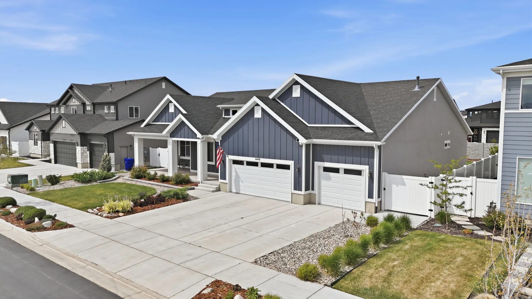 View of front facade featuring board and batten siding, a gate, concrete driveway, roof with shingles, and an attached garage