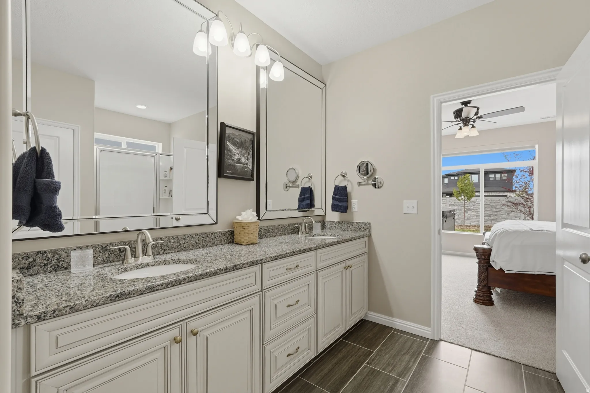 Ensuite bathroom with double vanity, a stall shower, dark carpet, and ceiling fan