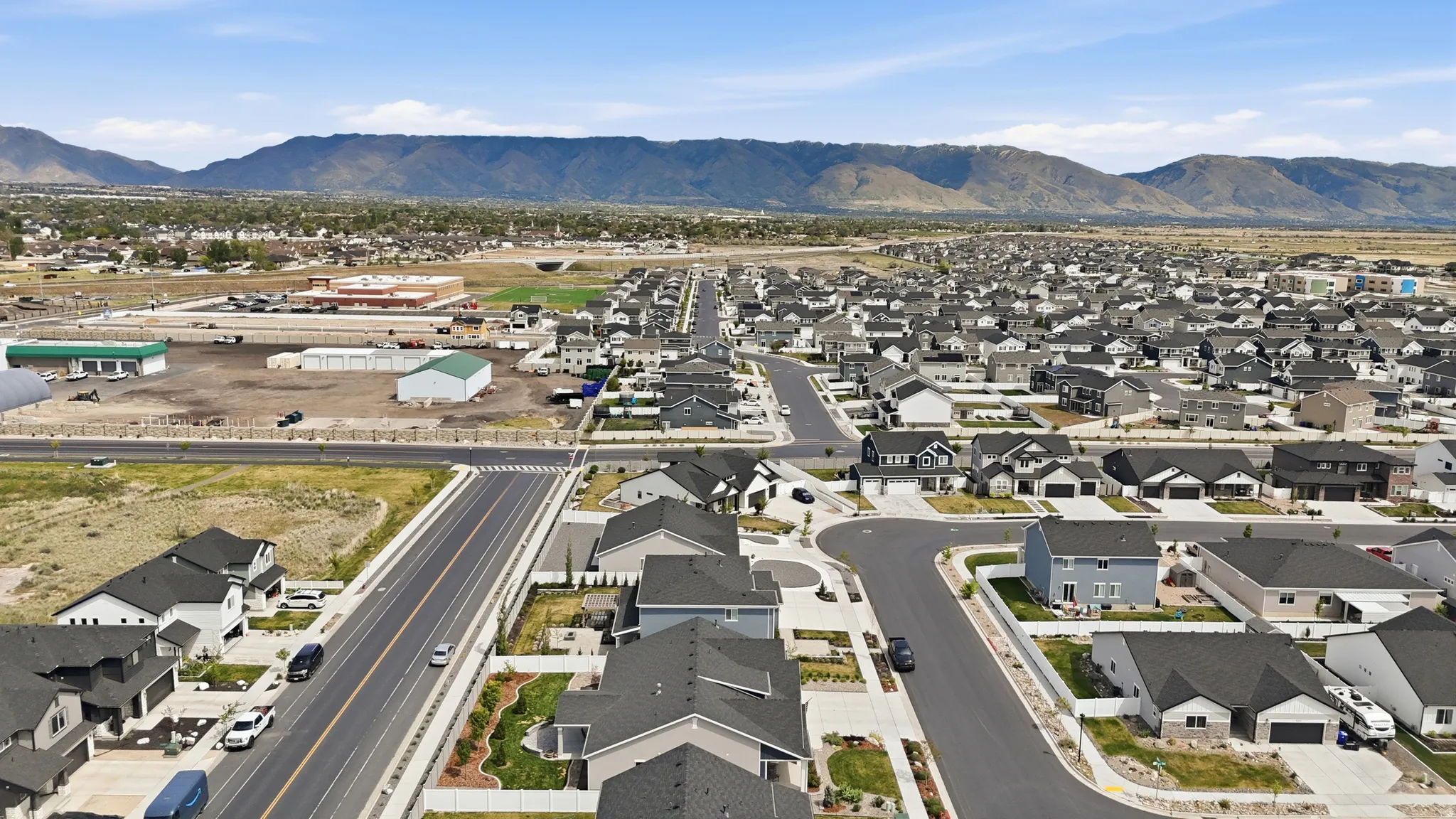 Aerial view of property and surrounding area featuring nearby suburban area and a mountain backdrop