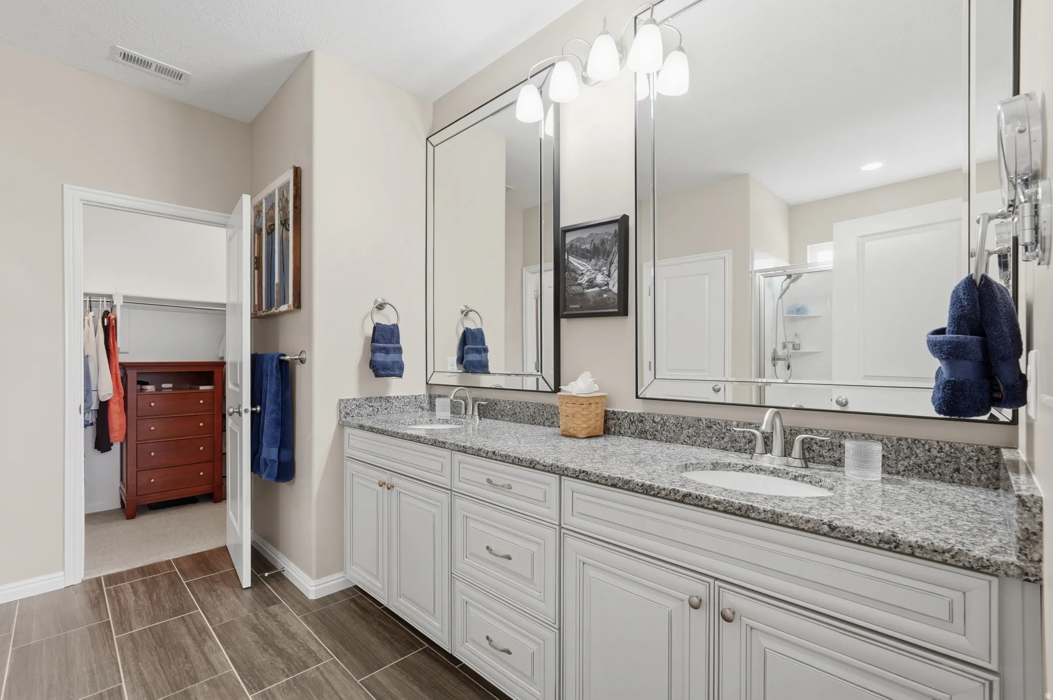 Full bath featuring double vanity, a stall shower, and a walk in closet