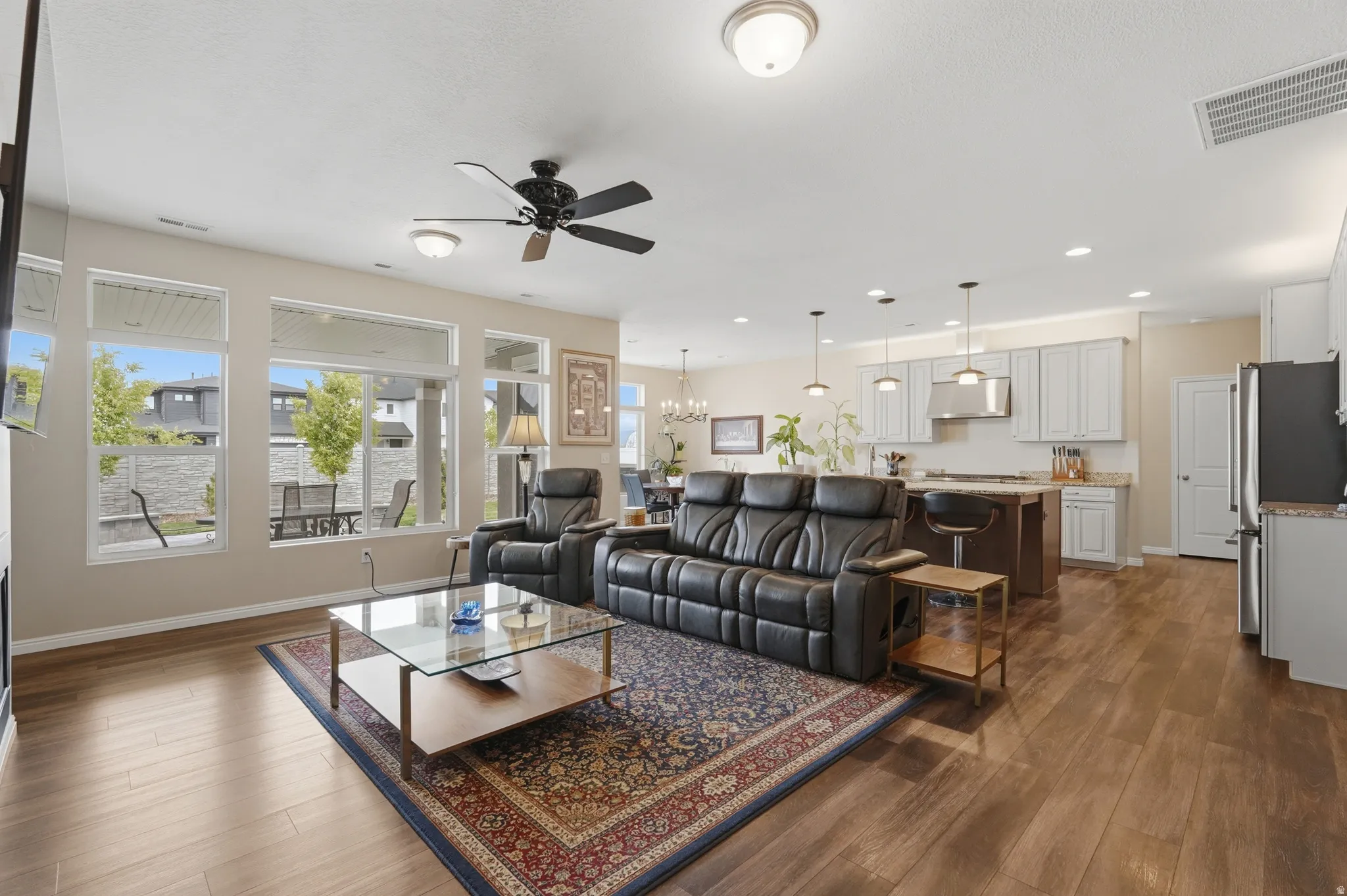Living room with hanging lights, a ceiling fan, and dark wood-style flooring