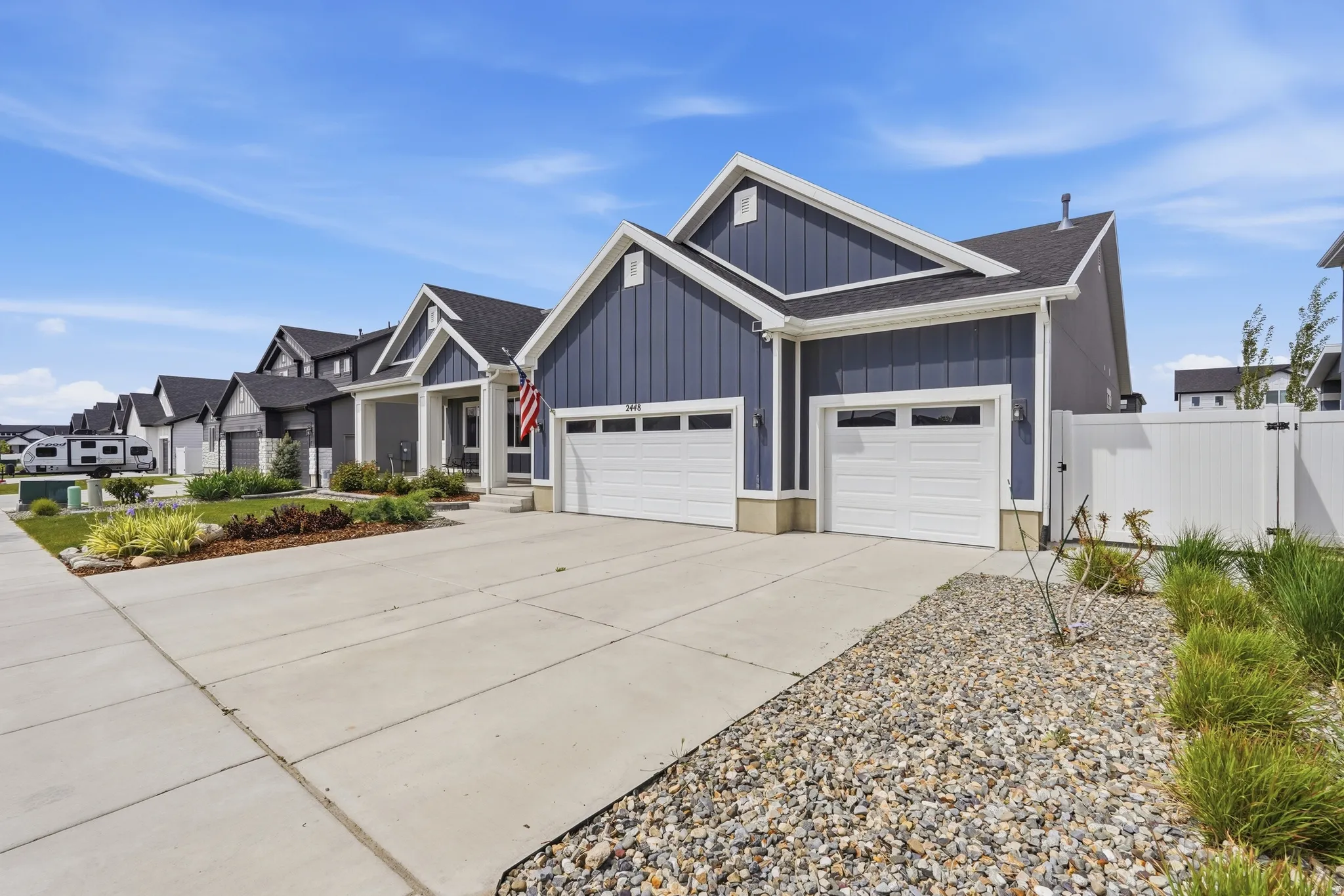 View of front of house with board and batten siding, an attached garage, driveway, roof with shingles, and a residential view