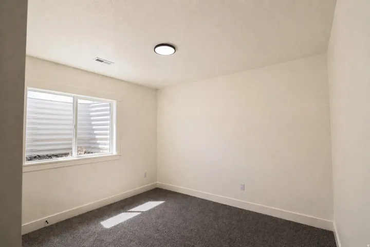 Unfurnished room with baseboards and dark colored carpet