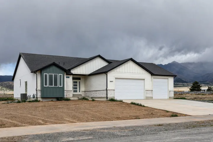 View of front of house featuring board and batten siding, driveway, a mountain view, a garage, and a shingled roof