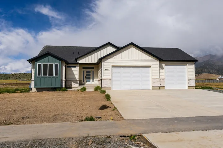 View of front of property with board and batten siding, an attached garage, concrete driveway, and roof with shingles