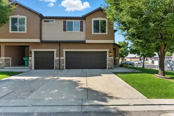 Traditional-style house with stucco siding, an attached garage, concrete driveway, and stone siding