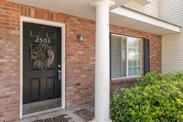 Doorway to property featuring brick siding and covered porch