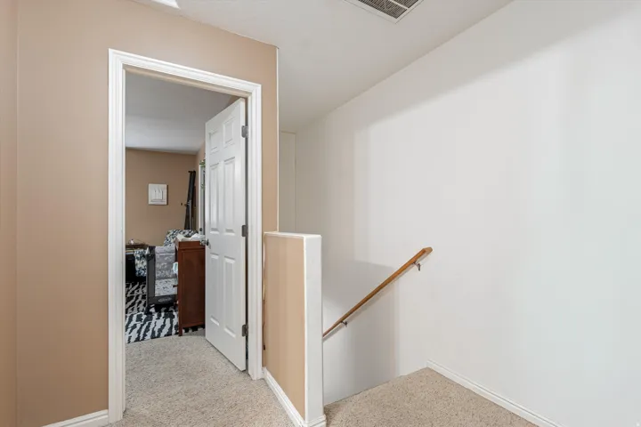 Hallway with an upstairs landing and light colored carpet