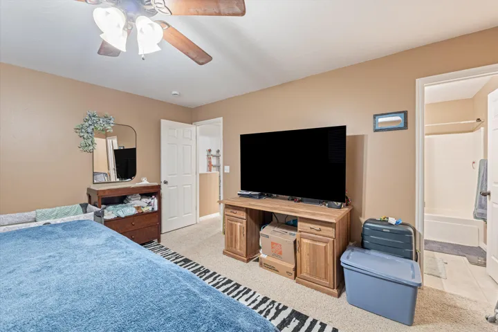 Bedroom featuring light colored carpet, a ceiling fan, and ensuite bathroom