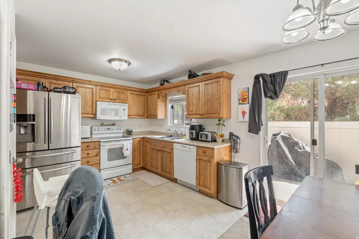 Kitchen featuring white appliances, light countertops, hanging lights, and wood finish cabinetry