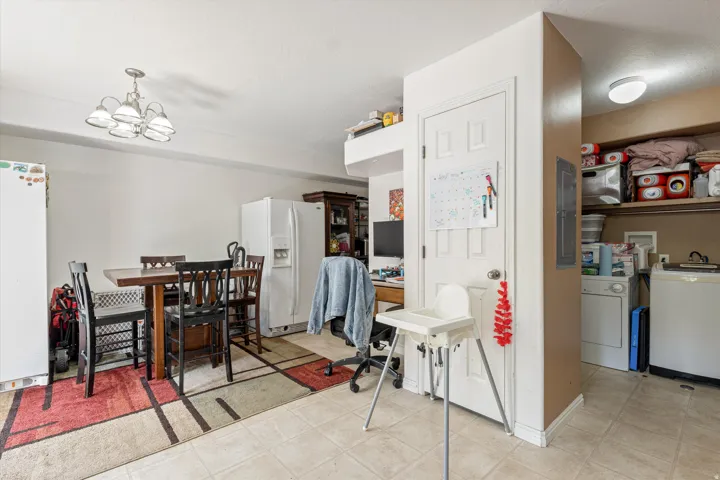 Dining area featuring washer / dryer, light tile patterned flooring, suspended lighting, and electric panel
