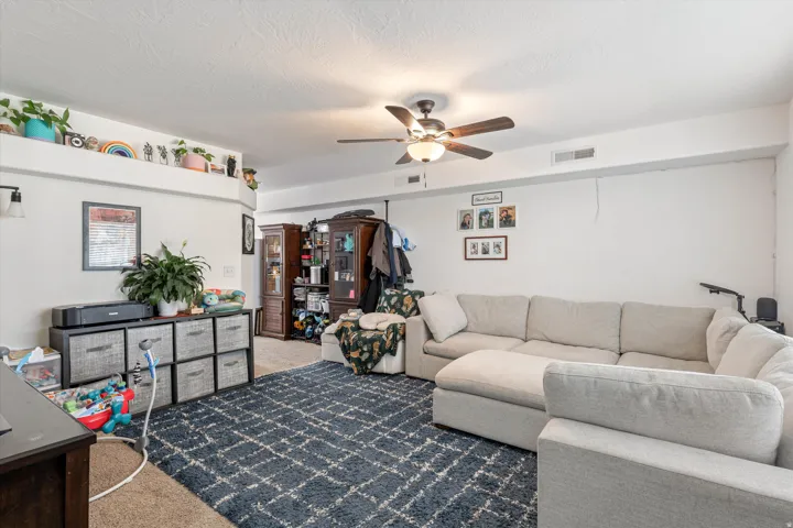 Carpeted living room featuring ceiling fan and a textured ceiling