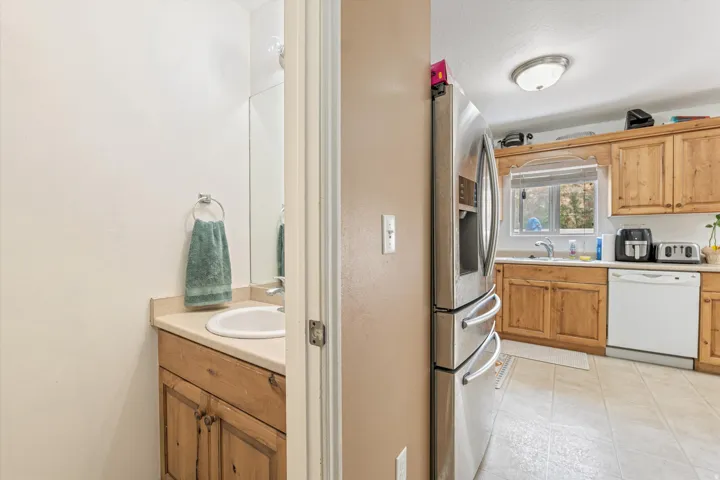 Kitchen with light countertops, stainless steel fridge with ice dispenser, dishwasher, and wood finish cabinetry