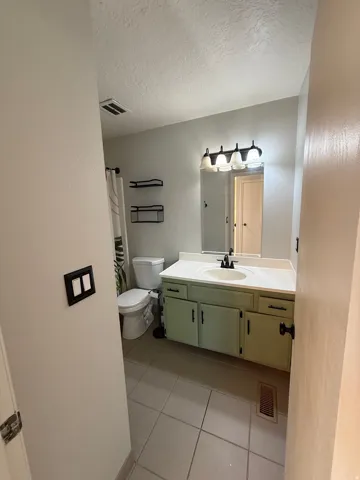Bathroom with vanity, light tile patterned floors, a textured ceiling, and a shower with curtain