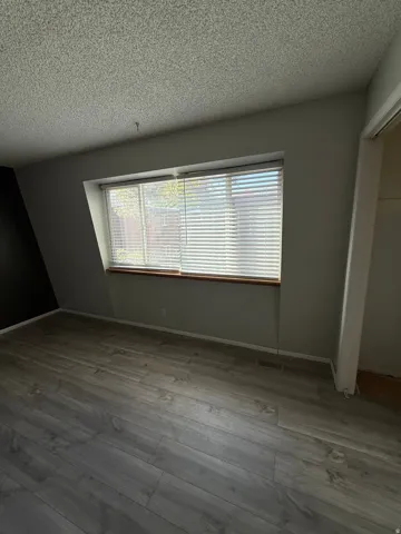 Unfurnished bedroom featuring a textured ceiling, a closet, and wood finished floors