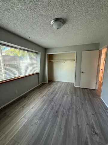 Unfurnished bedroom featuring a textured ceiling, light wood-style flooring, and a closet