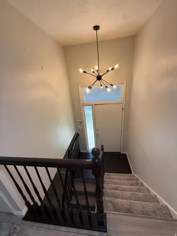 Stairs with a chandelier and a high textured ceiling