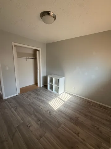 Unfurnished bedroom featuring a closet, dark wood finished floors, and a textured ceiling