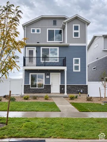 Three-story exterior featuring a mix of horizontal lap and vertical board-and-batten siding, stone veneer accents, an upper-level balcony with metal railings, and a concrete front walkway