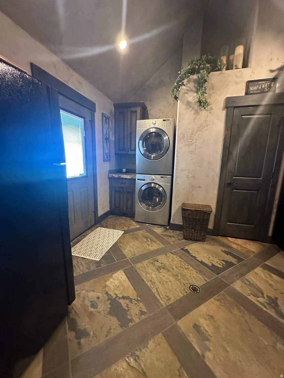 Laundry room featuring stacked washing machine and dryer and inlaid floor details
