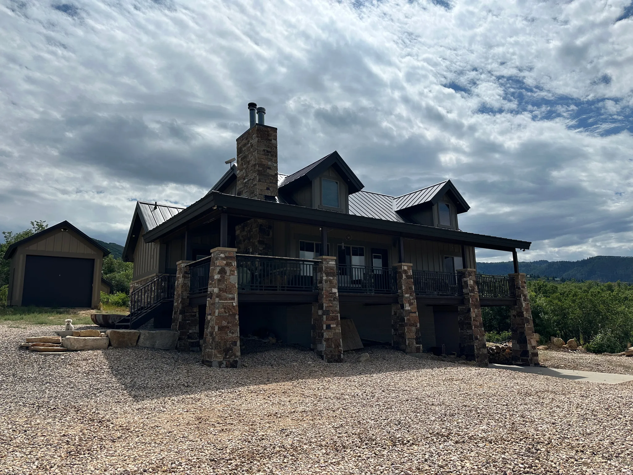 Front of cabin featuring a standing seam roof, board and batten siding, a porch, and stone siding
