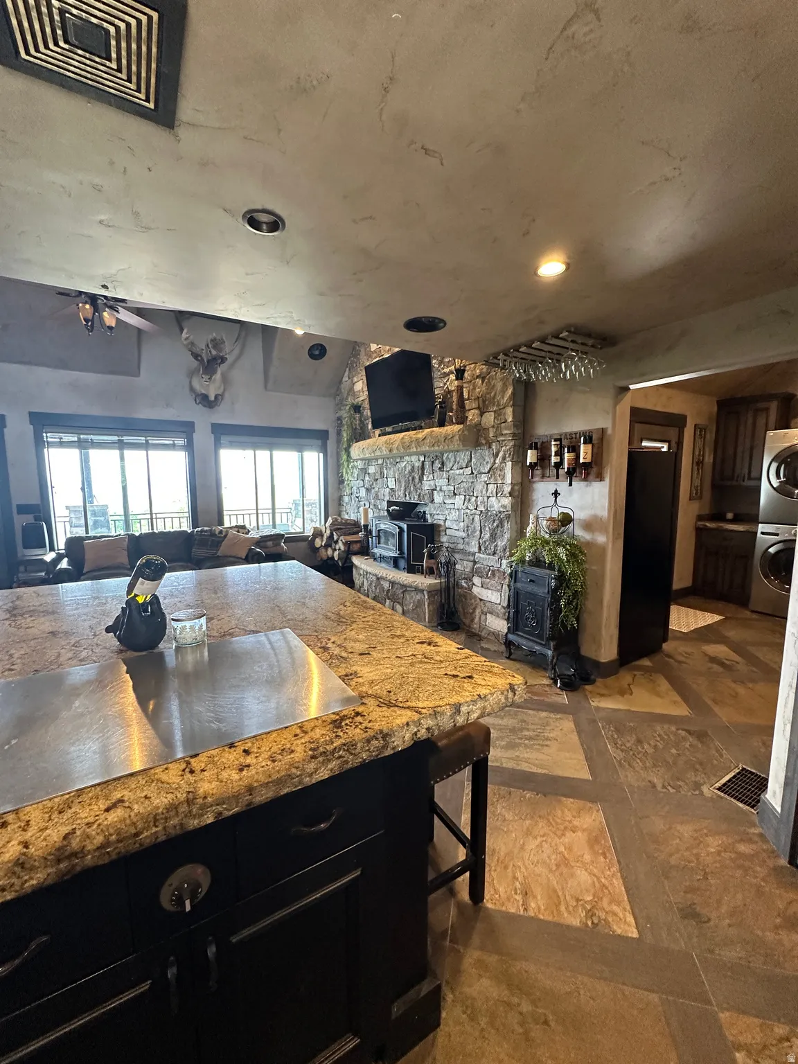Kitchen with dark cabinetry, open floor plan, light stone countertops, and freestanding refrigerator