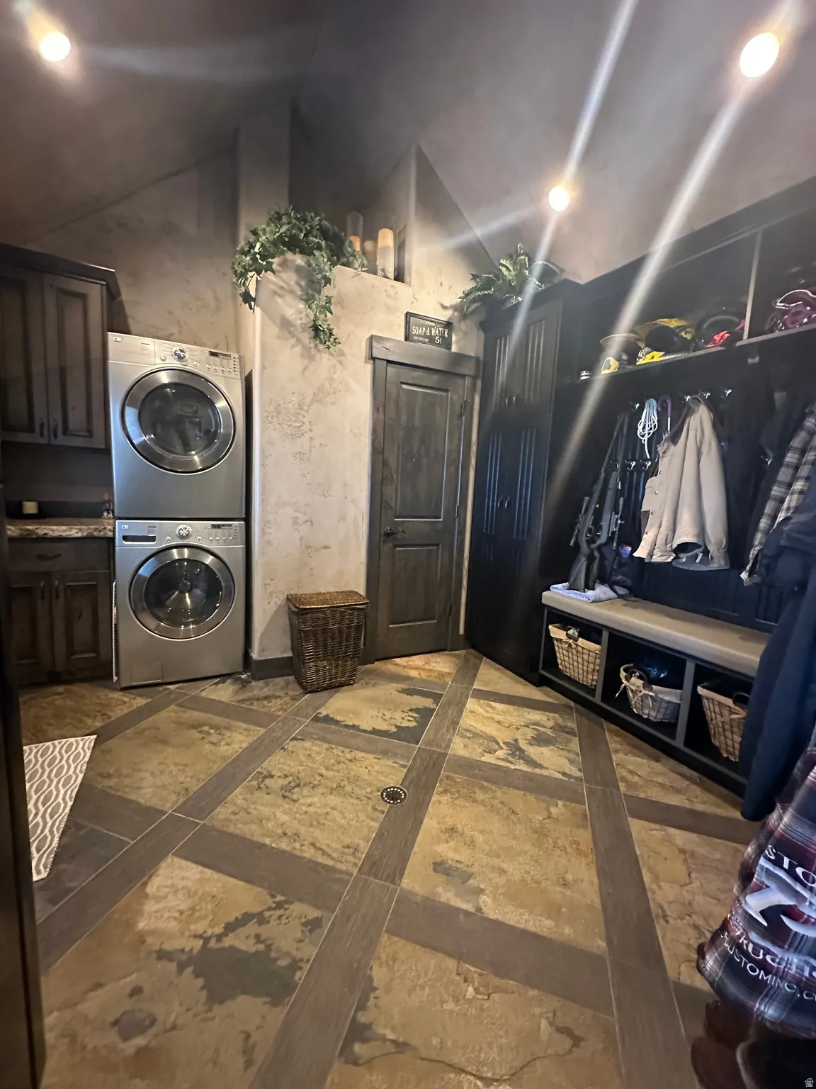 Laundry area featuring stacked washer / dryer, lofted ceiling, inlaid floor details, and recessed lighting